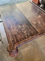 Grande table en bois patiné brun-rouge reposants sur quatre pieds...