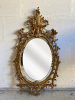 Miroir ovale en bois stuqué doré à décor de rinceaux,...