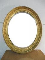 Miroir ovale en bois et stuc doré à décor de...