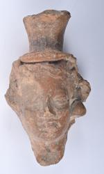Tête de figurine en céramique modelée
coiffée d'un kalathos, avec traces...