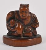 Netsuké en bois sculpté à décor d'un homme assis avec...