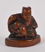 Netsuké en bois sculpté à décor d'un homme assis avec...