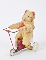 Petit ours mécanique
en peluche, sur un tricycle en tôle laquée...