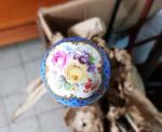 Une ombrelle en bois clair pommeau en porcelaine à décor...