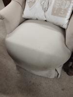 Un fauteuil crapaud garni de tissu beige (tâches)