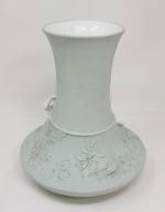 Un vase en porcelaine à décor blanc sur fond vert...
