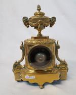 Une pendule en bronze doré à décor d'urne aux têtes...