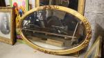 Un grand miroir ovale, cadre bois et stuc doré à...