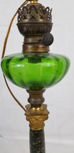 Une lampe à pétrole - réservoir en verre coloré reposant...