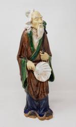 Une statuette en poterie vernissée polychrome - représentant un vieux...