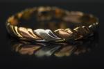 Bracelet articulé trois tons d'or, à décor de frise de...
