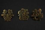 Trois petites broches en or jaune, figurant des caractères chinois....